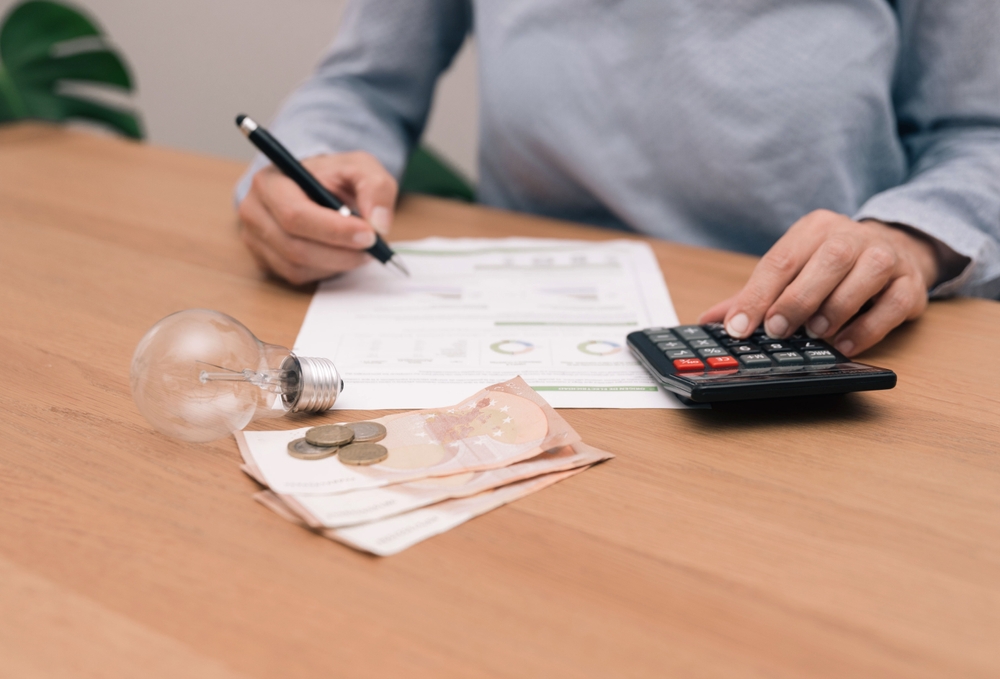 Close,Up,Of,Unrecognizable,Person,Analyzing,Electricity,Bill,With,Calculator,