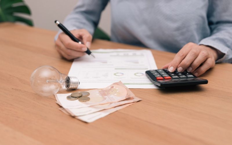 Close,Up,Of,Unrecognizable,Person,Analyzing,Electricity,Bill,With,Calculator,